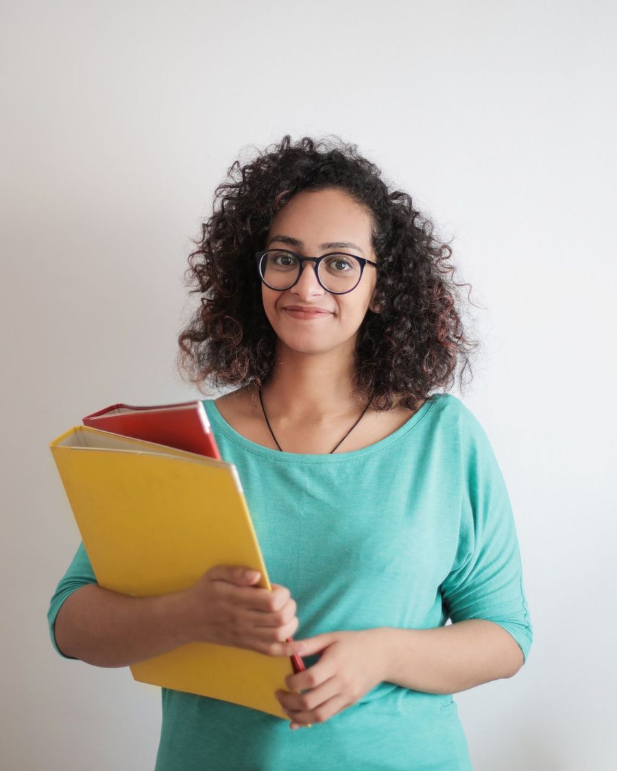 Portrait of a smiling woman in a teal top holding folders