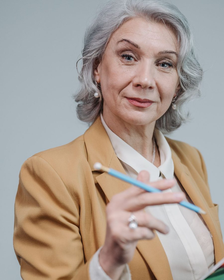 Portrait of a woman in a tan blazer holding a pencil